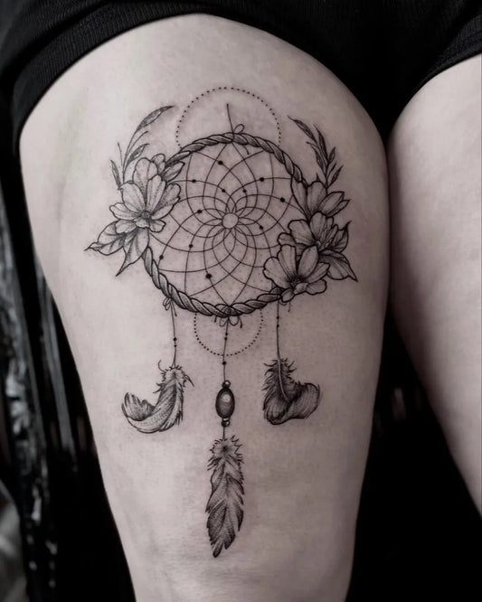 Medium Blackwork Dream Catcher with Flowers and Feathers Tattoo on Women Thigh by @inkedbyjuls