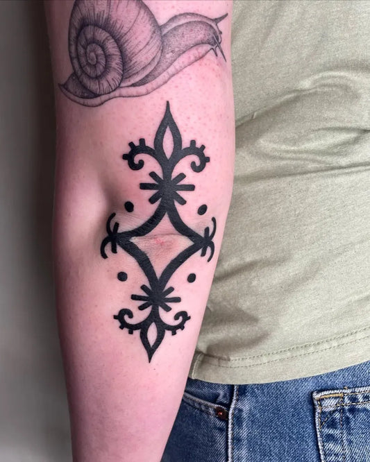 Medium Blackwork Fleur de lis and Snail Tattoo on Men Elbow by @ashley_thorne_tattoo