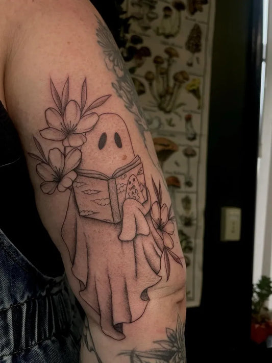 Medium Blackwork Ghost with Flowers and Book Tattoo on Women Arm by @inkedby.g