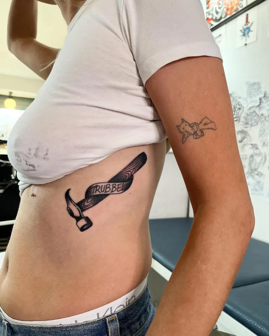Medium Blackwork Hammer and Ribbon Tattoo on Women Rib by @victor_aka_chili