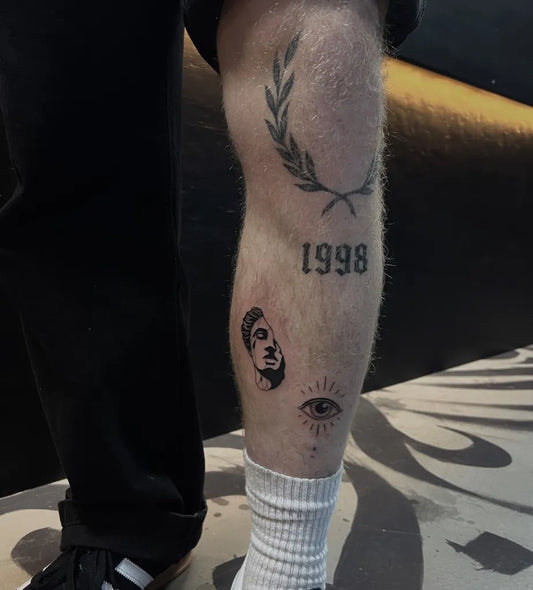 Medium Blackwork Laurel Wreath Birth Year and Eye Tattoo on Men Thigh by @inkdustry__