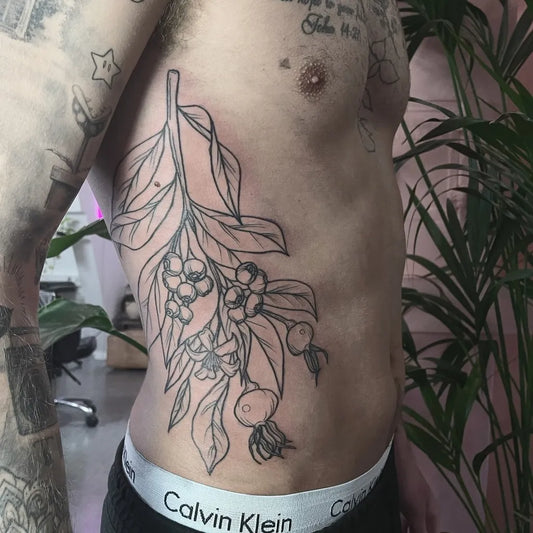 Medium Blackwork Leaf and Berry Branch Tattoo on Men Rib by @studio4.no