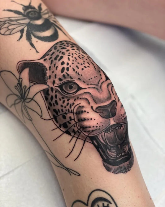 Medium Blackwork Leopard Bee Lily Tattoo on Women Knee by @evanbyrnetattoo