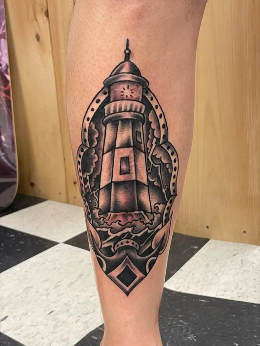 Medium Blackwork Lighthouse with Waves Tattoo on Men Leg by @americananchortattooco