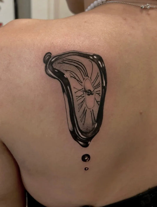 Medium Blackwork Melting Clock Tattoo on Women Shoulder by @tattoo_circus_bientina