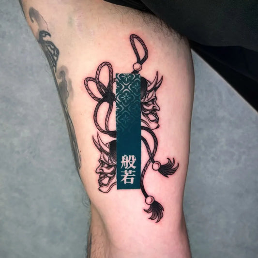 Medium Blackwork Oni Mask with Rope and Tassels on Men Thigh Tattoo by @mako.tattoo_tokyo
