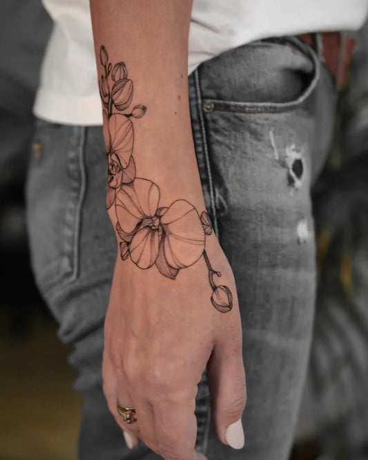 Medium Blackwork Orchid Tattoo on Women Wrist by @essential.tattoo