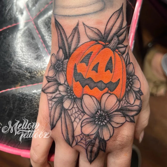 Medium Blackwork Pumpkin and Flowers Halloween Tattoo on Women Hand by @mellowtattooz
