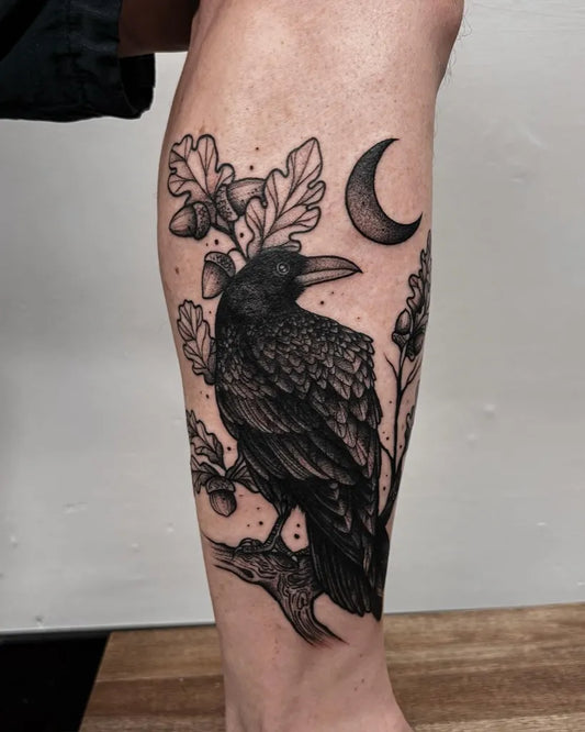Medium Blackwork Raven Acorn Crescent on Women Leg Tattoo by @marianamisticatattoo