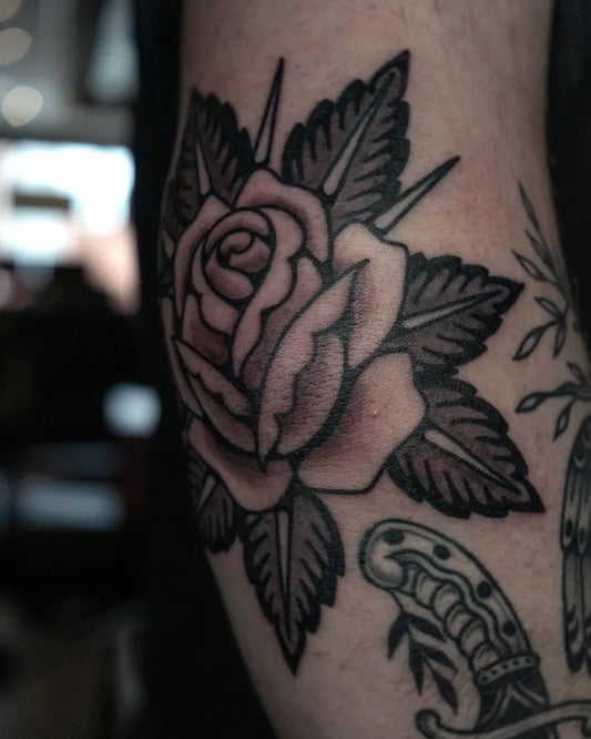 Medium Blackwork Rose and Dagger Tattoo on Men Elbow by @yuri.tattoos