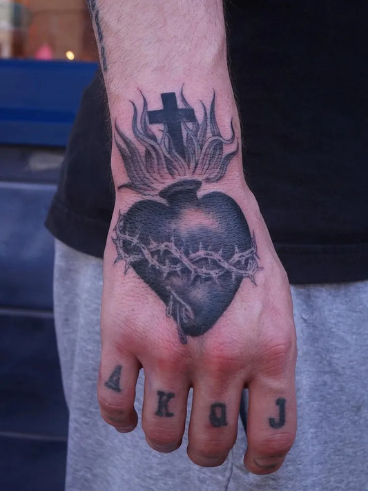 Medium Blackwork Sacred Heart with Crown of Thorns and Flames Tattoo on Men Hand by @jackthomasnewton