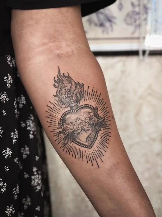 Medium Blackwork Sacred Heart with Flames and Wings Tattoo on Women Arm by @hexelilithtattoos