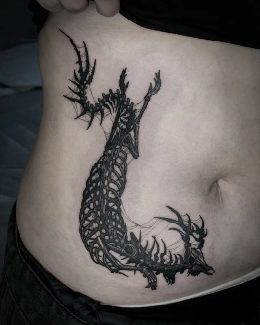 Medium Blackwork Skeletal Dragon Tattoo on Women Stomach by @jellyjoy.tt
