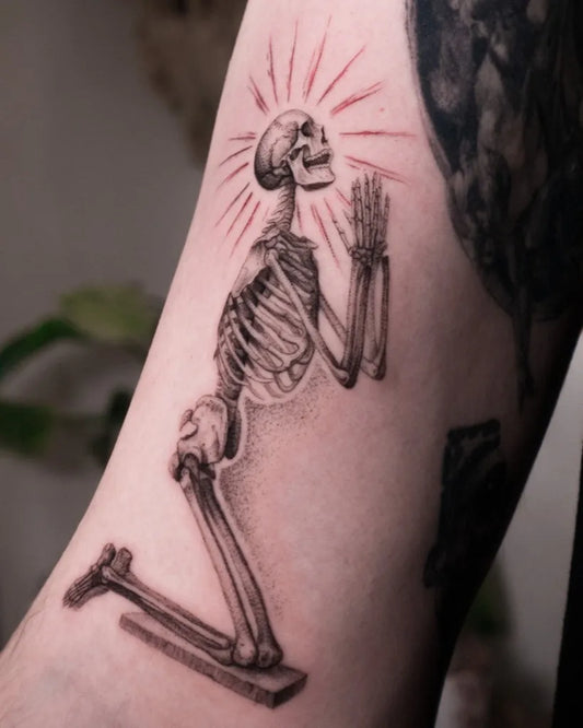 Medium Blackwork Skeleton with Halo and Praying Hands Tattoo on Men Arm by @sudeozpaklar