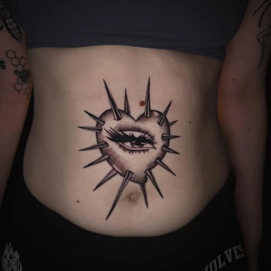 Medium Blackwork Spiked Heart Eye on Women Stomach Tattoo by @_kailey.lynn.tattoos