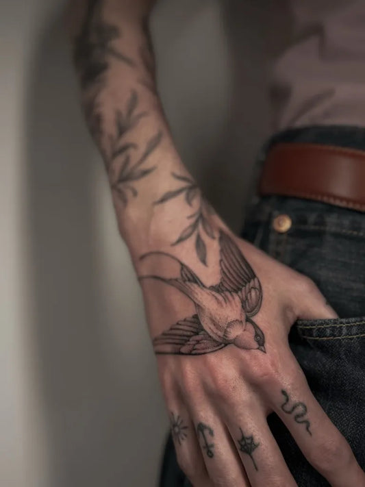 Medium Blackwork Swallow and Flowers Tattoo on Men Arm by @tigerlily.tattooss