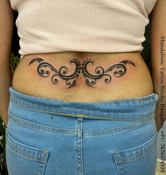 Medium Blackwork Symmetrical Floral Vines Tattoo on Women Lower Back by @mandalistictattoostudio