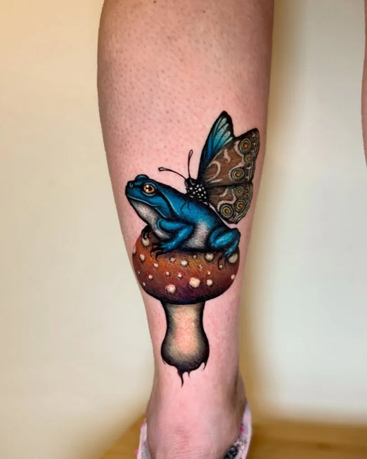 Medium Blue Frog on Mushroom with Butterfly Tattoo on Women Leg by @tetar_ttt