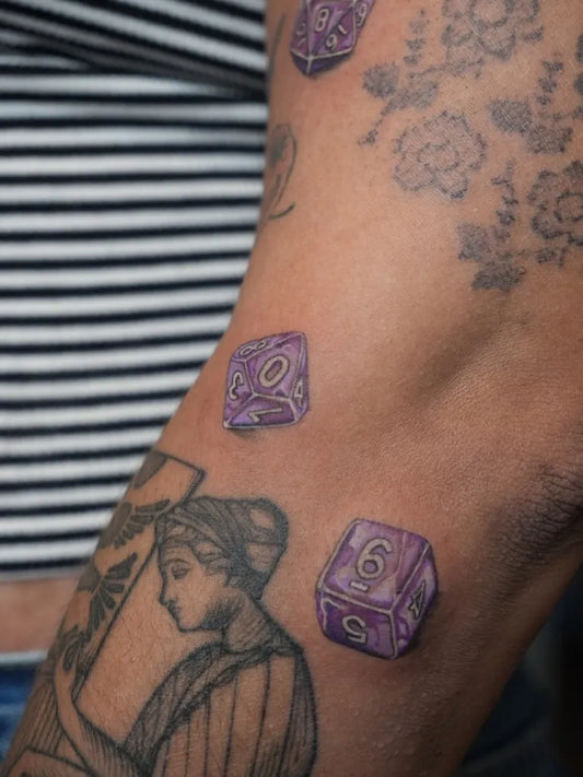 Medium Color Realism Dice and Flowers Tattoo on Women Arm by @obscura.tattoo