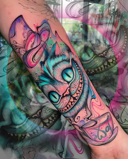 Medium Colorful Cheshire Cat Tea Cup Tattoo on Women Arm by @amaltheatattoos