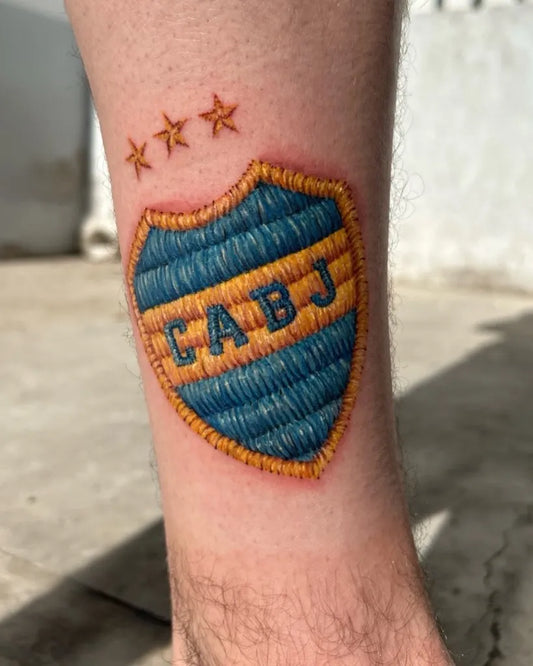 Medium Embroidery CABJ Shield Tattoo on Men Leg by @ivana.ibar.tattoo