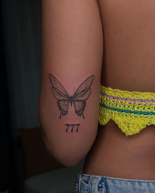 Fine Line Butterfly and 777 on Women Upper Arm Tattoo by @butterfly_._tattoo