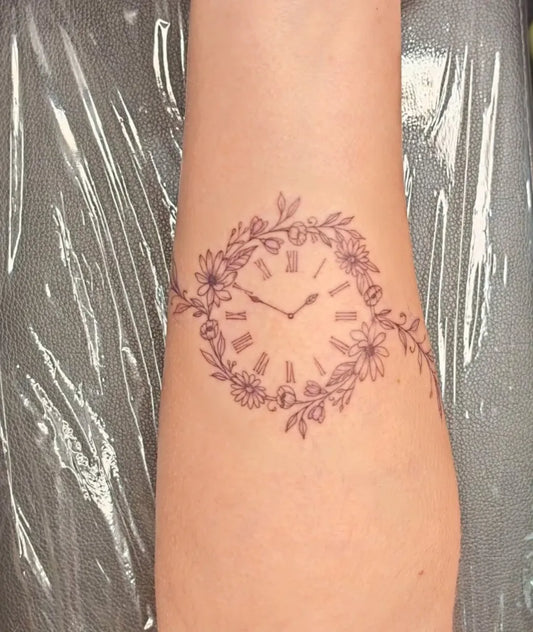 Medium Fine Line Clock and Floral Wreath Tattoo on Women Wrist by @sacredtree_ink