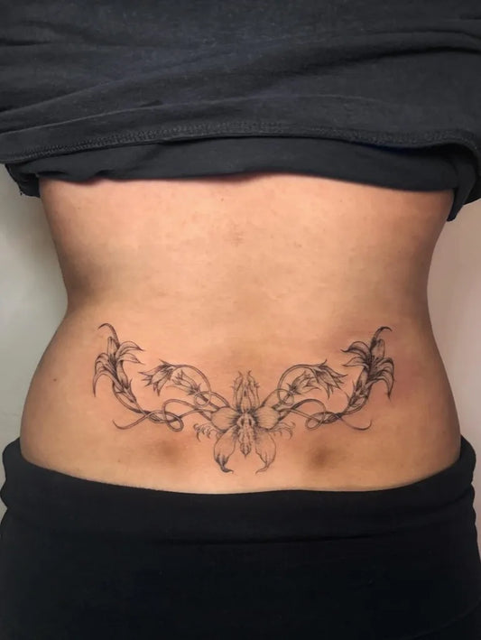 Medium Fine Line Floral Vine Tattoo on Women Lower Back by @liz.tattooz
