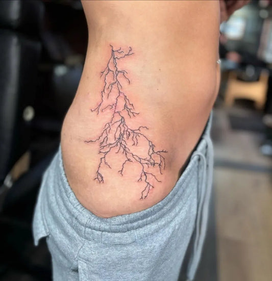 Medium Fine Line Lightning Bolt Tattoo on Women Side by @zodiac_tattoo_company