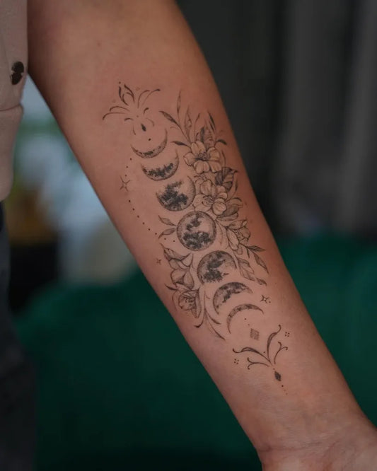 Medium Fine Line Moon Phases and Flowers Tattoo on Women Arm by @dark_botanist_ink