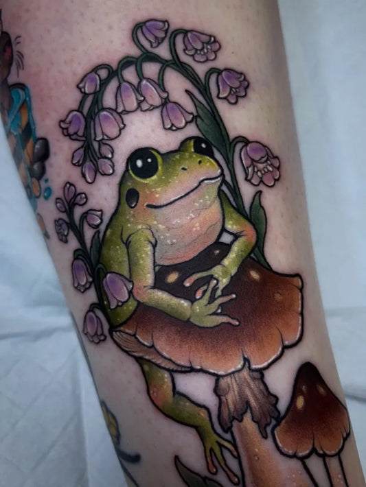 Medium Illustrative Frog with Lily of the Valley and Mushroom Tattoo on Women Leg by @angelskye.tattoo