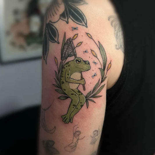 Medium Illustrative Frog with net and foliage Tattoo on Women Arm by @neonhearttattoo