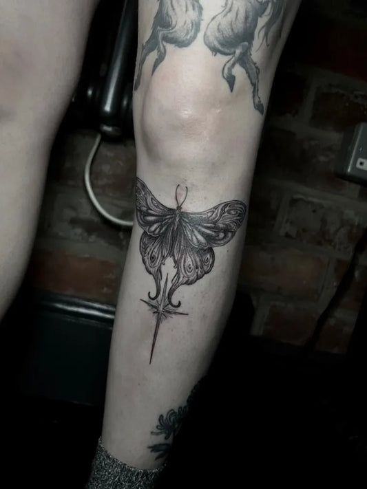 Medium Illustrative Moth and Cross Tattoo on Women Thigh by @bethblxcktattoo