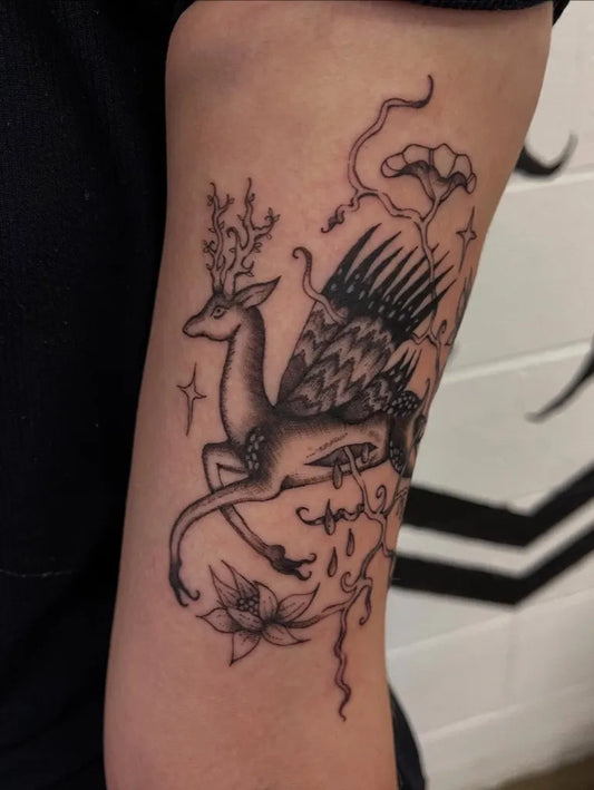 Medium Illustrative Mythical Deer with Wings and Flowers Tattoo on Women Arm by @oatmealqueeen