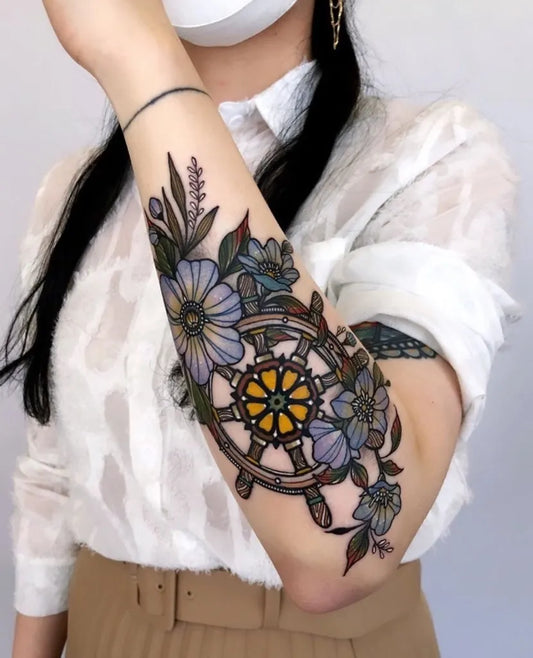 Medium Illustrative Wheel Flowers Butterfly Nautical Tattoo on Women Arm by @outofstepb