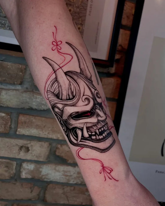 Medium Japanese Oni Mask with Red Ribbons on Women Arm Tattoo by @kitsunevio.ink