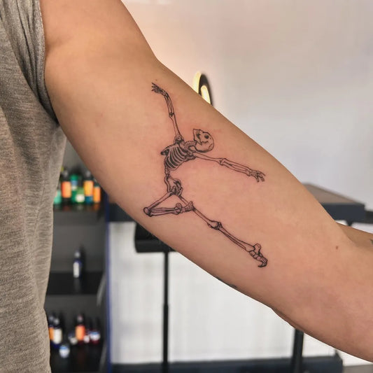 Medium Linework Dancing Skeleton Tattoo on Men Bicep by @cry.baby.alexandra