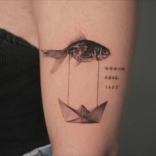 Medium Minimalist Goldfish and Paper Boat Tattoo on Women Arm by @gaiafilacchioni.tattoo
