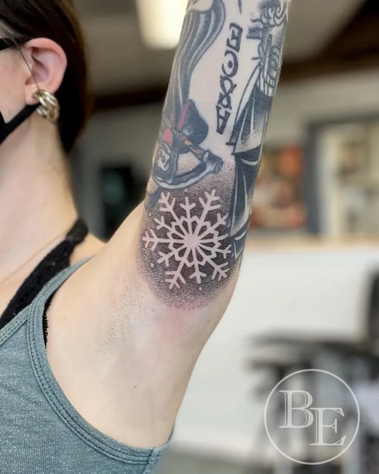 Medium Negative Space Snowflake Tattoo on Women Arm by @brenna.eagan