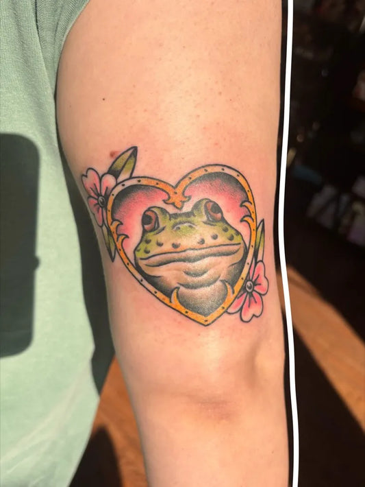 Medium Neo Traditional Frog in Heart with Flowers Tattoo on Women Arm by @ink_bugg