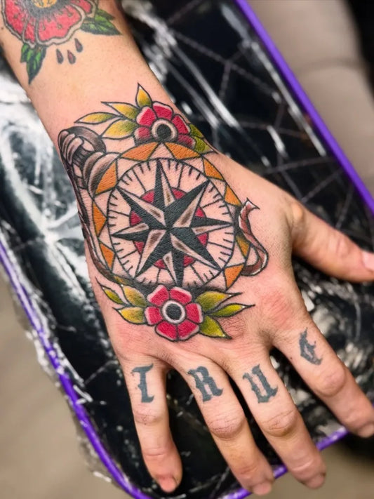 Medium Neotraditional Compass Rose with Flowers Nautical Tattoo on Women Hand by @emilycolgantattoos
