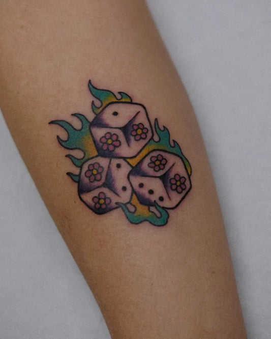 Medium Neotraditional Dice with Flowers and Flames Tattoo on Women Arm by @zuespokes