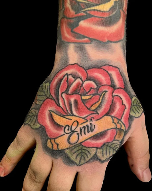 Medium Neotraditional Red Rose with Ribbon on Men Hand Tattoo by @drucraig