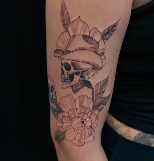 Medium Neotraditional Skull with Hat and Flowers on Women Arm Tattoo by @inkszi