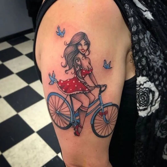 Medium New School Pin Up Girl Biking With Birds Tattoo on Women Arm by @seventattoostudio