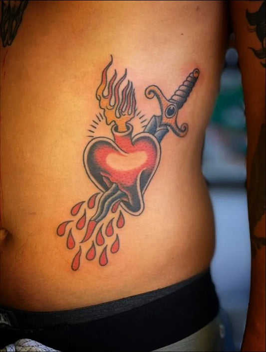 Medium Old School Sacred Heart with Dagger Tattoo on Men Rib by @mangata.tattoostudio