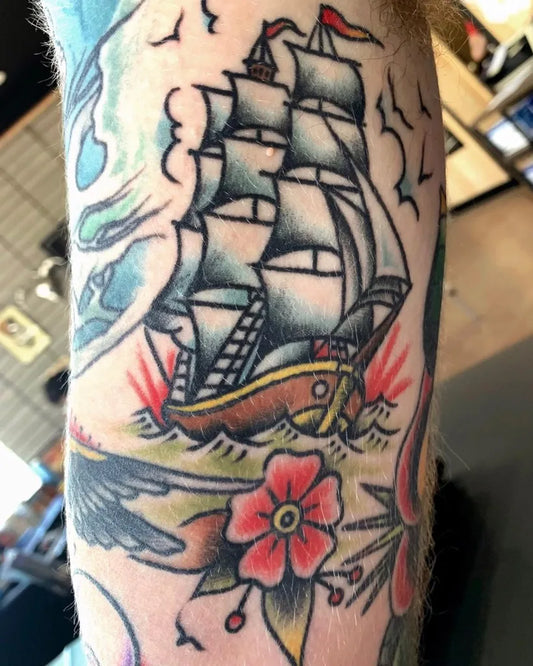 Medium Old School Sailing Ship and Flower Nautical Tattoo on Men Arm by @chrisnaderertattoo