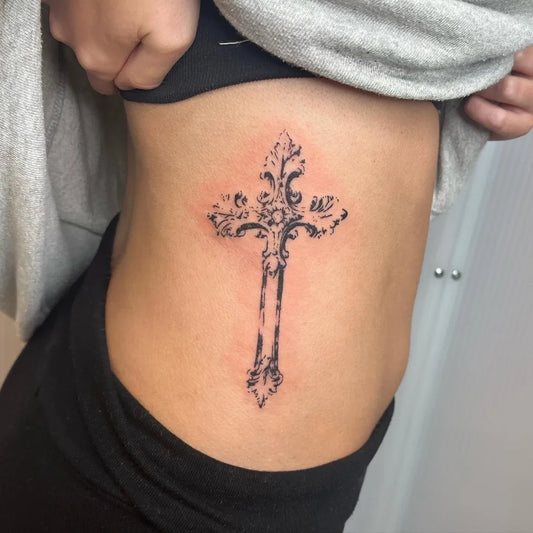 Medium Ornate Cross with Floral Elements on Women Rib Tattoo by @hammermontana.tatts
