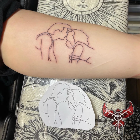 Medium Outline Kissing Couple Tattoo on Women Arm by @tattoo.nicoleburman