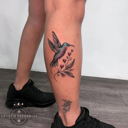 Medium Realism Hummingbird with Flowers and Leaves on Women Leg Tattoo by @artisticencountertattoobali